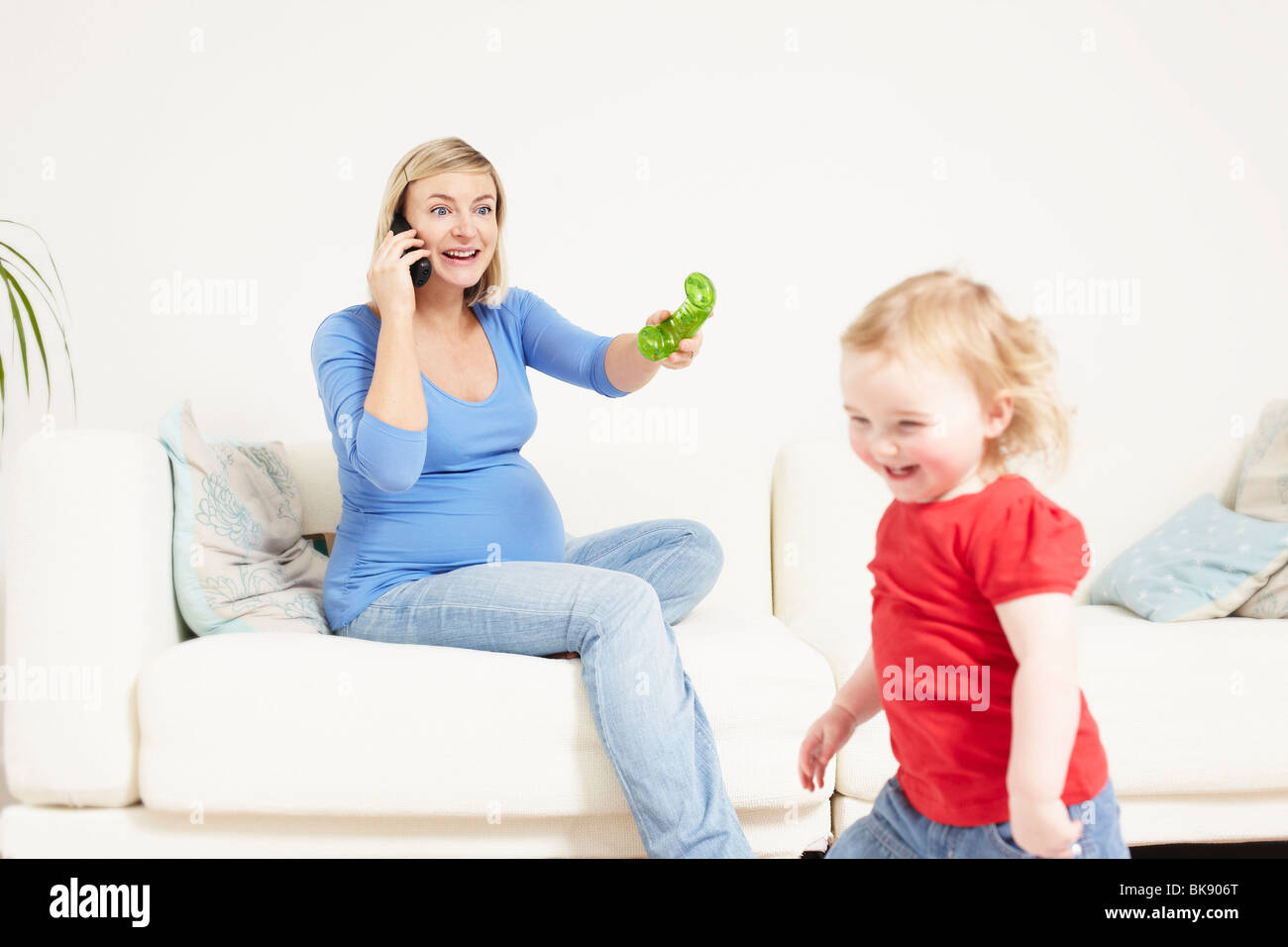 Pregnant woman on phone with toddler Banque D'Images
