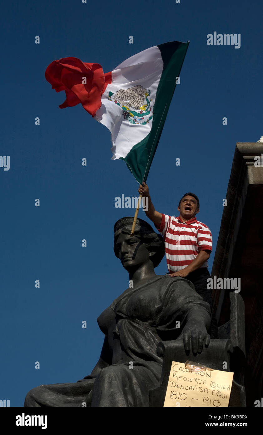 Un homme au drapeau du Mexique en ondes l'Ange de l'indépendance monument pendant une manifestation dans la ville de Mexico, 15 octobre 2009. Banque D'Images