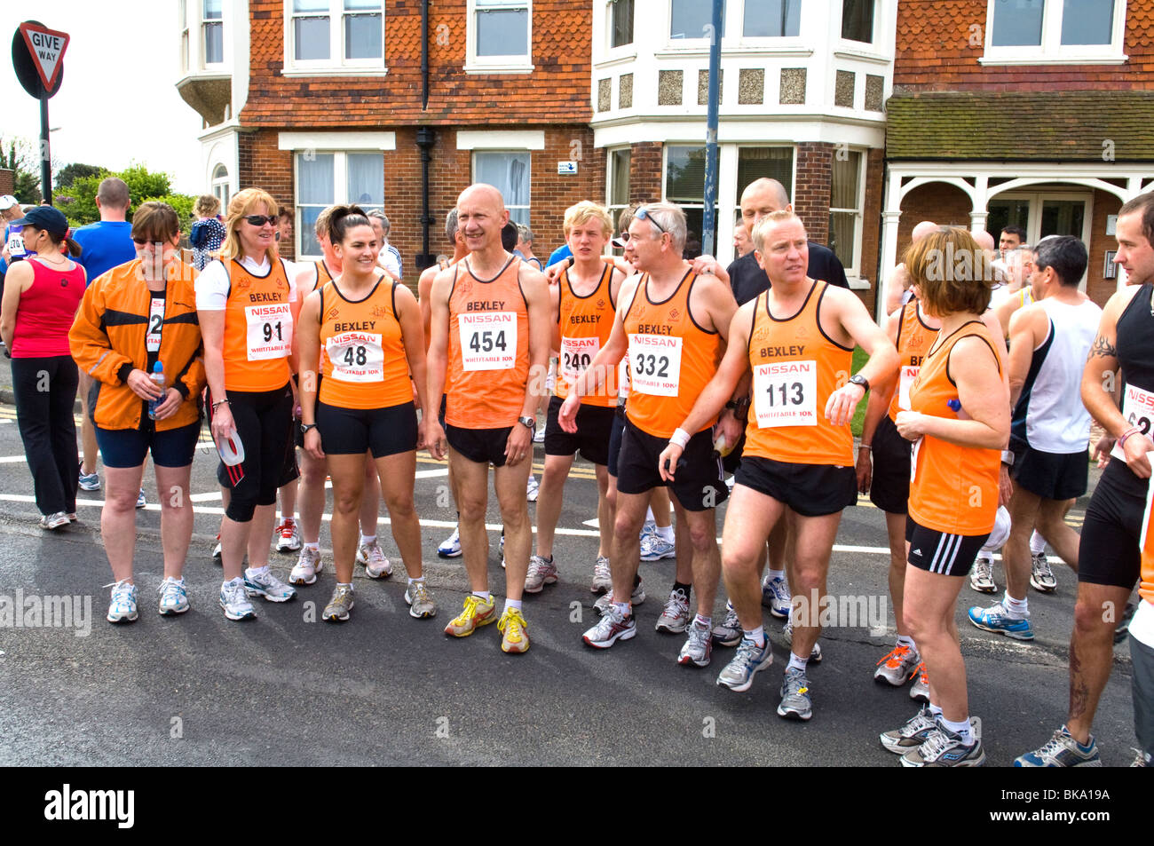 Des groupes de coureurs la collecte dans la rue avant le début d'une 10km course de bienfaisance de Bexley qui sont tous des orange. Banque D'Images