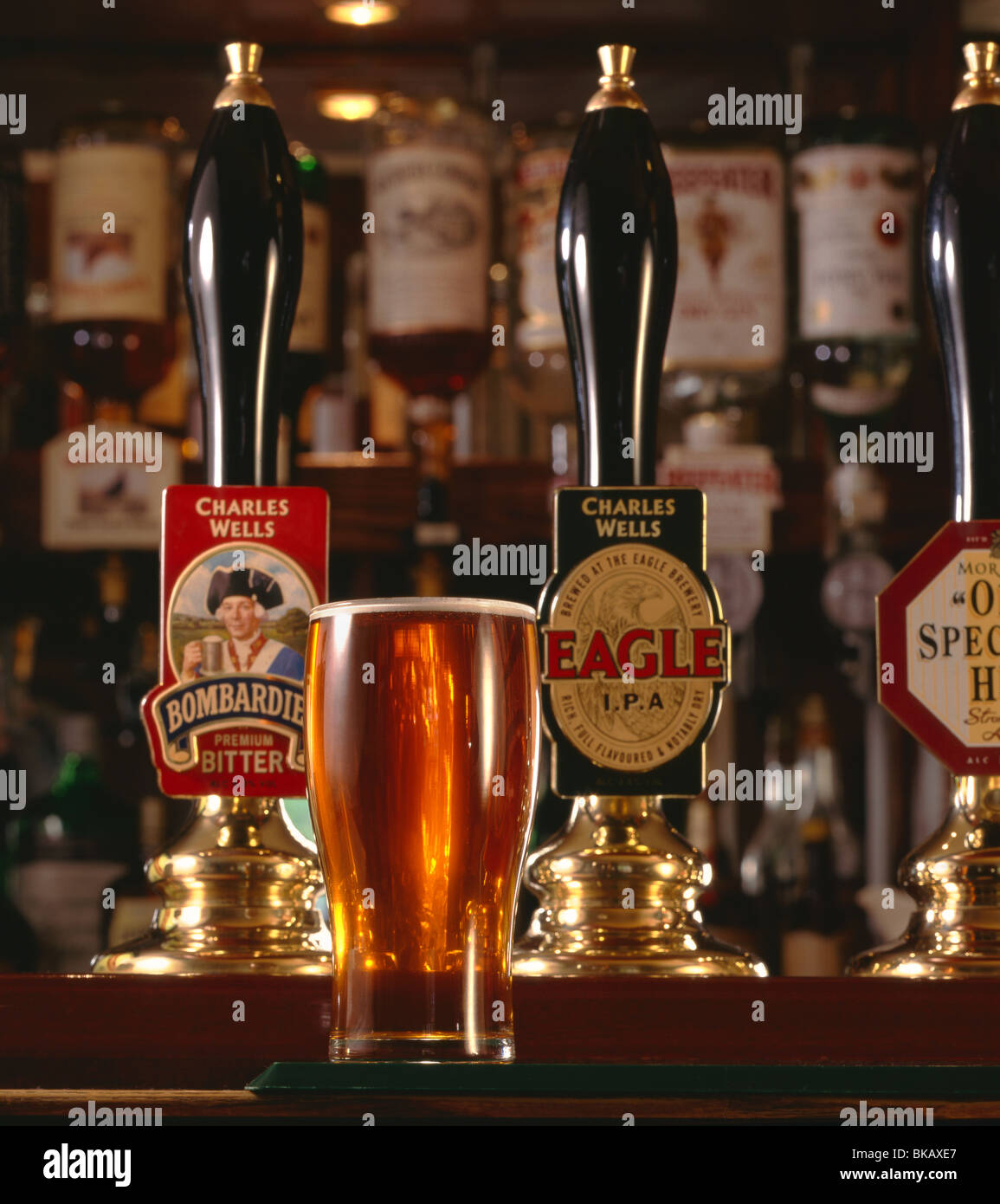 Pinte de bitter servi dans l'atmosphère typique pub anglais avec sélection de poignées de pompe offrant divers ales Banque D'Images