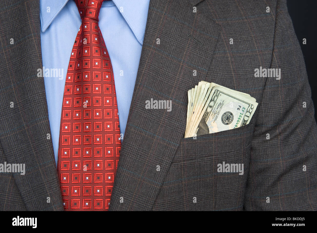 Un homme portant un costume et une cravate avec de l'argent qui sort de sa poche. Banque D'Images