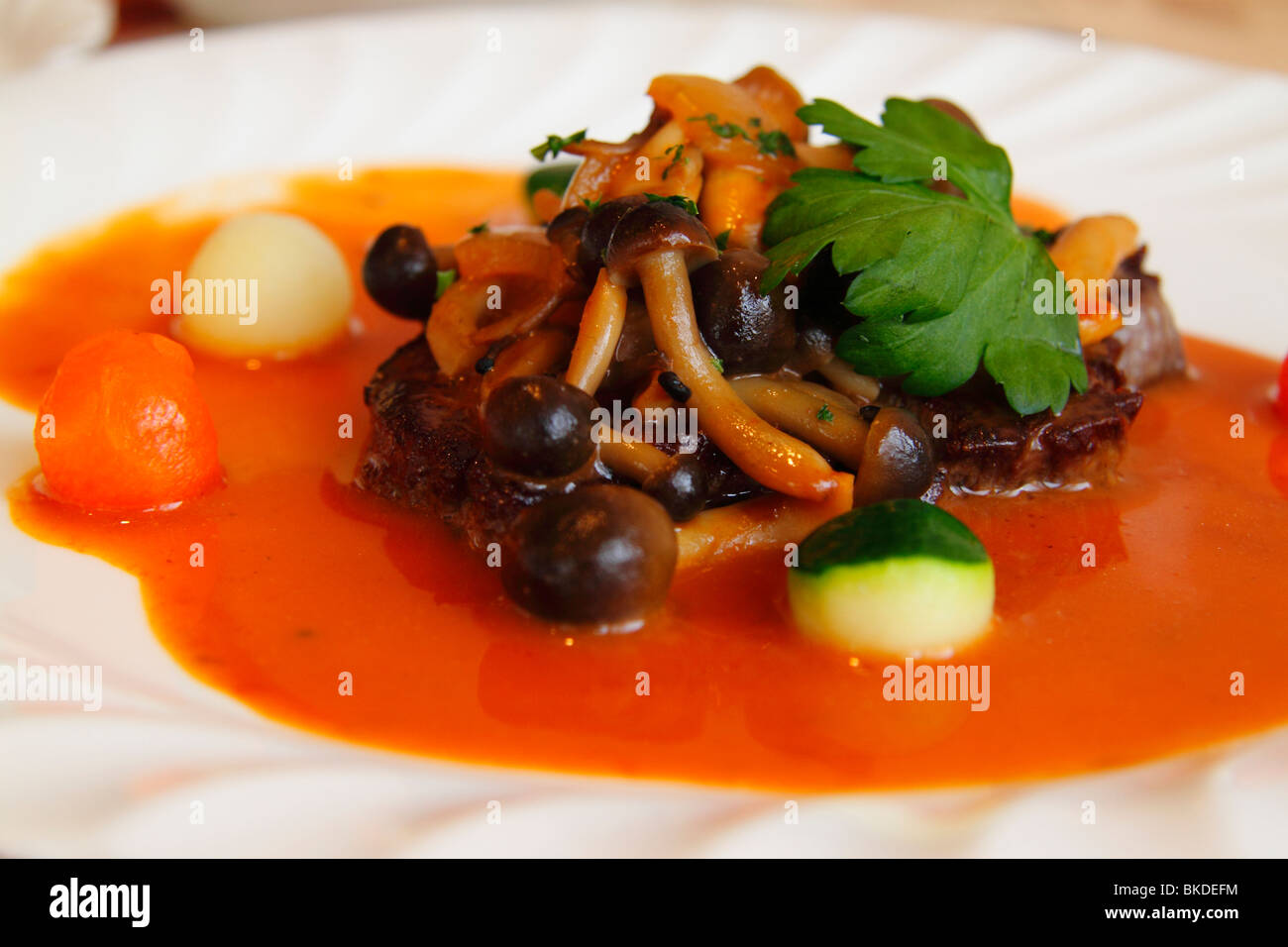 Un plat de viande servis dans un bistro français de Kyoto décorées avec des champignons, des légumes et de la sauce sauce orange vif. Banque D'Images