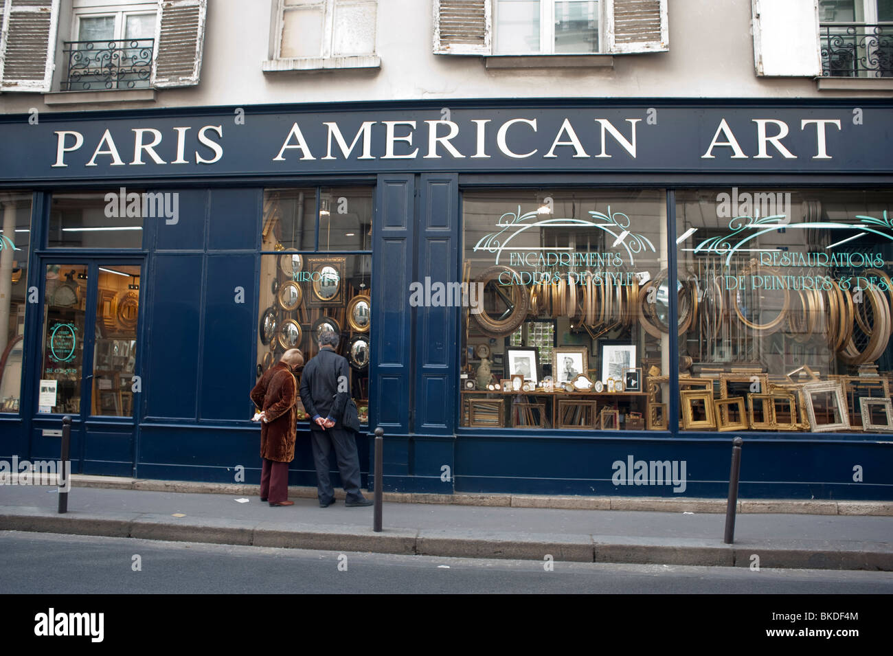 Shopping à deux fenêtres, magasin de cadrage d'images dans le quartier latin, « Paris American Art », seniors à l'extérieur de la boutique (le nom de la boutique a été changé) fenêtre Paris vintage Banque D'Images