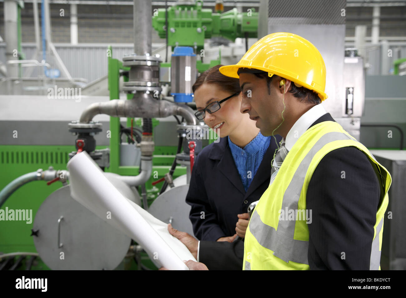 Travailleur industriel femelle à mâle asiatique avec des plans au directeur d'usine. Banque D'Images