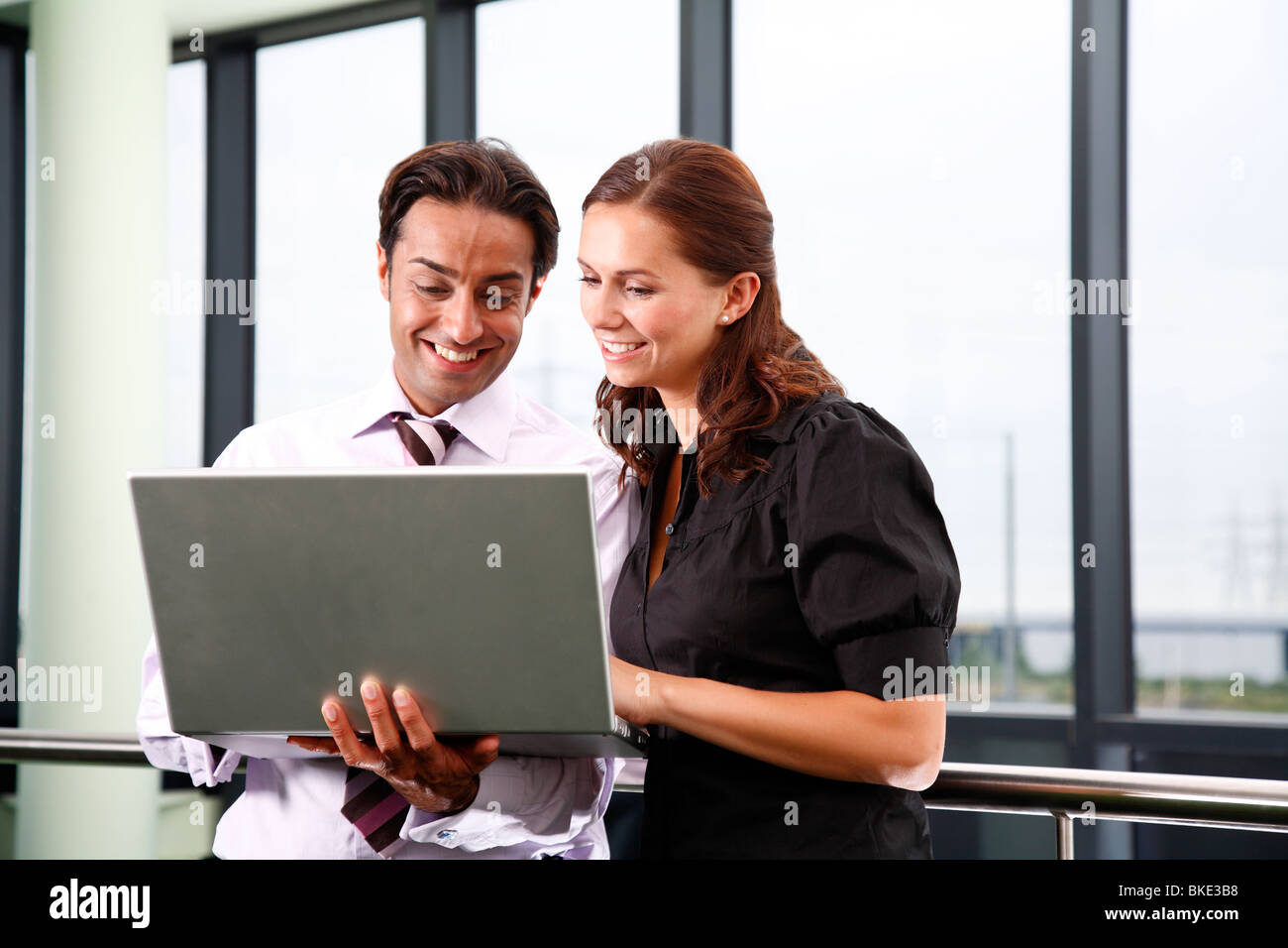 Asian male et femelle blanche des employés de bureau en bureau pour ordinateur portable à l'aide de l'environnement contemporain. Banque D'Images