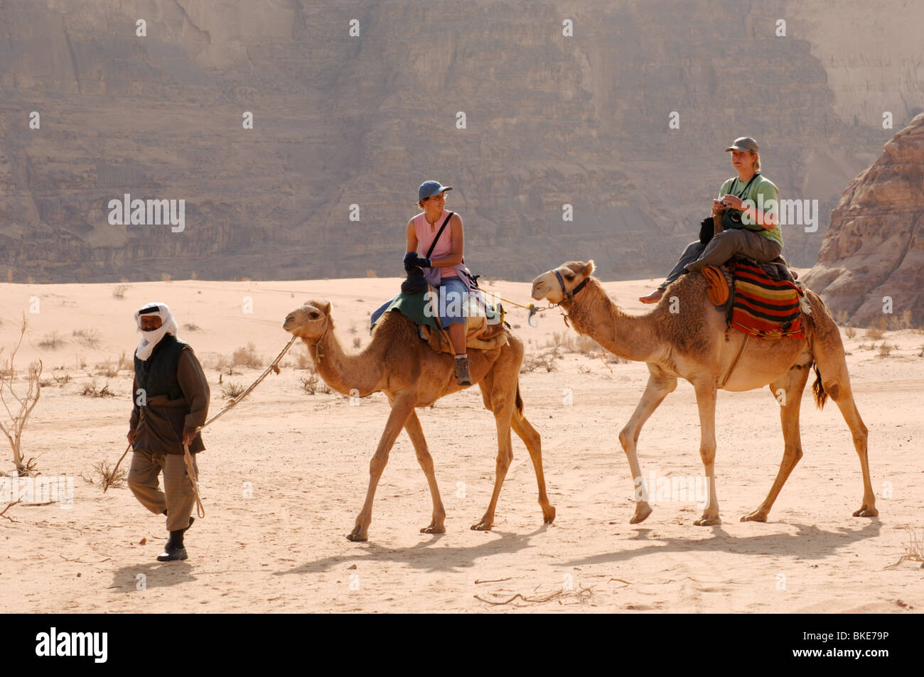 Guide bédouin et visiteurs sur les chameaux, Wadi Rum, Jordanie Zone protégée Banque D'Images