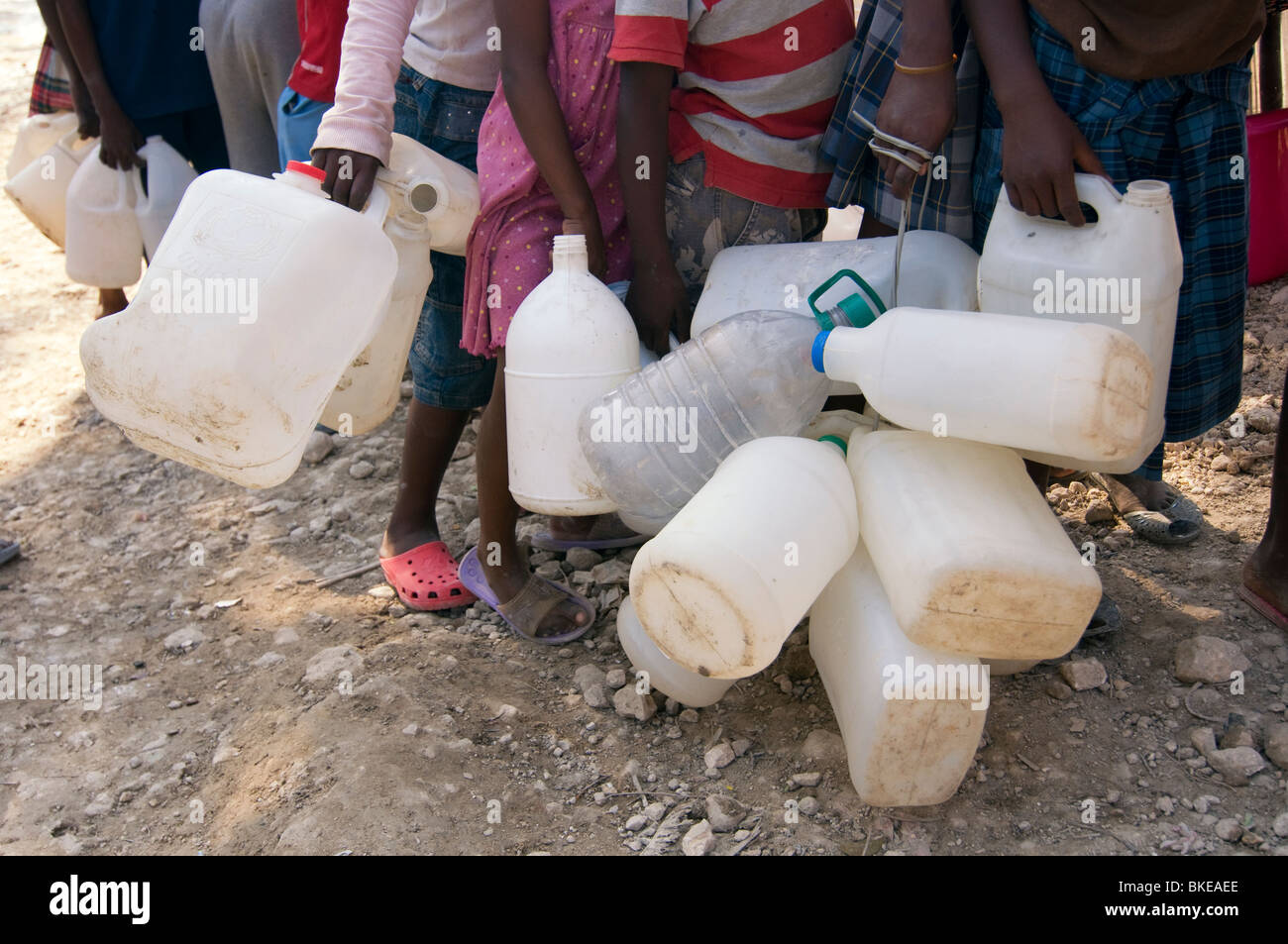 Les personnes titulaires d'attente les récipients en plastique pour l'alimentation en eau potable à Port-au-Prince, Haïti Banque D'Images