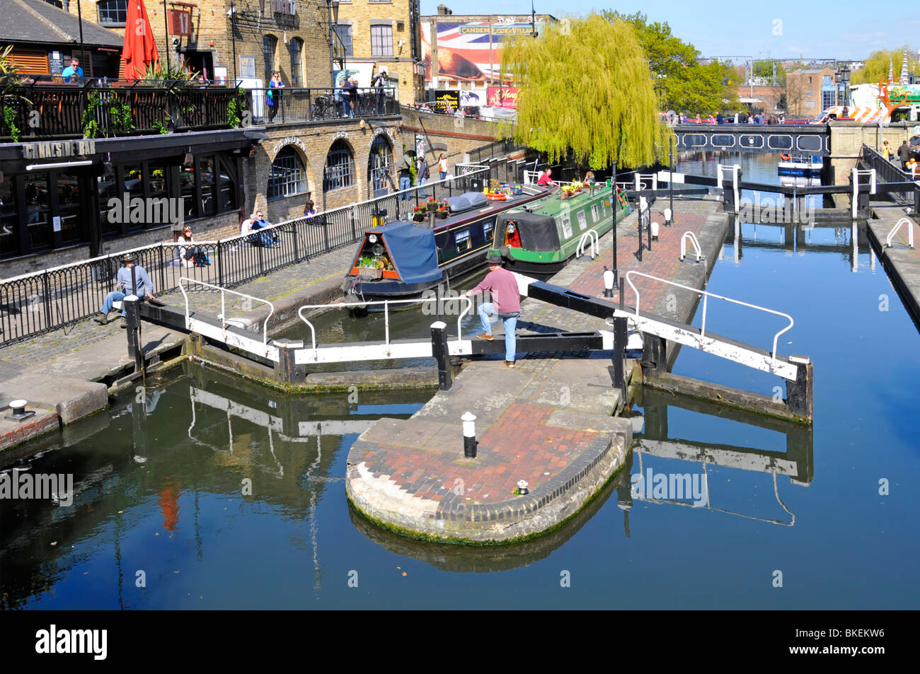 Vue sur les portes fermées, paysage urbain ensoleillé et bateaux étroits Dans Camden Lock sur Regents Canal avec saule pleureur Au-delà du nord de Londres Angleterre Royaume-Uni Banque D'Images