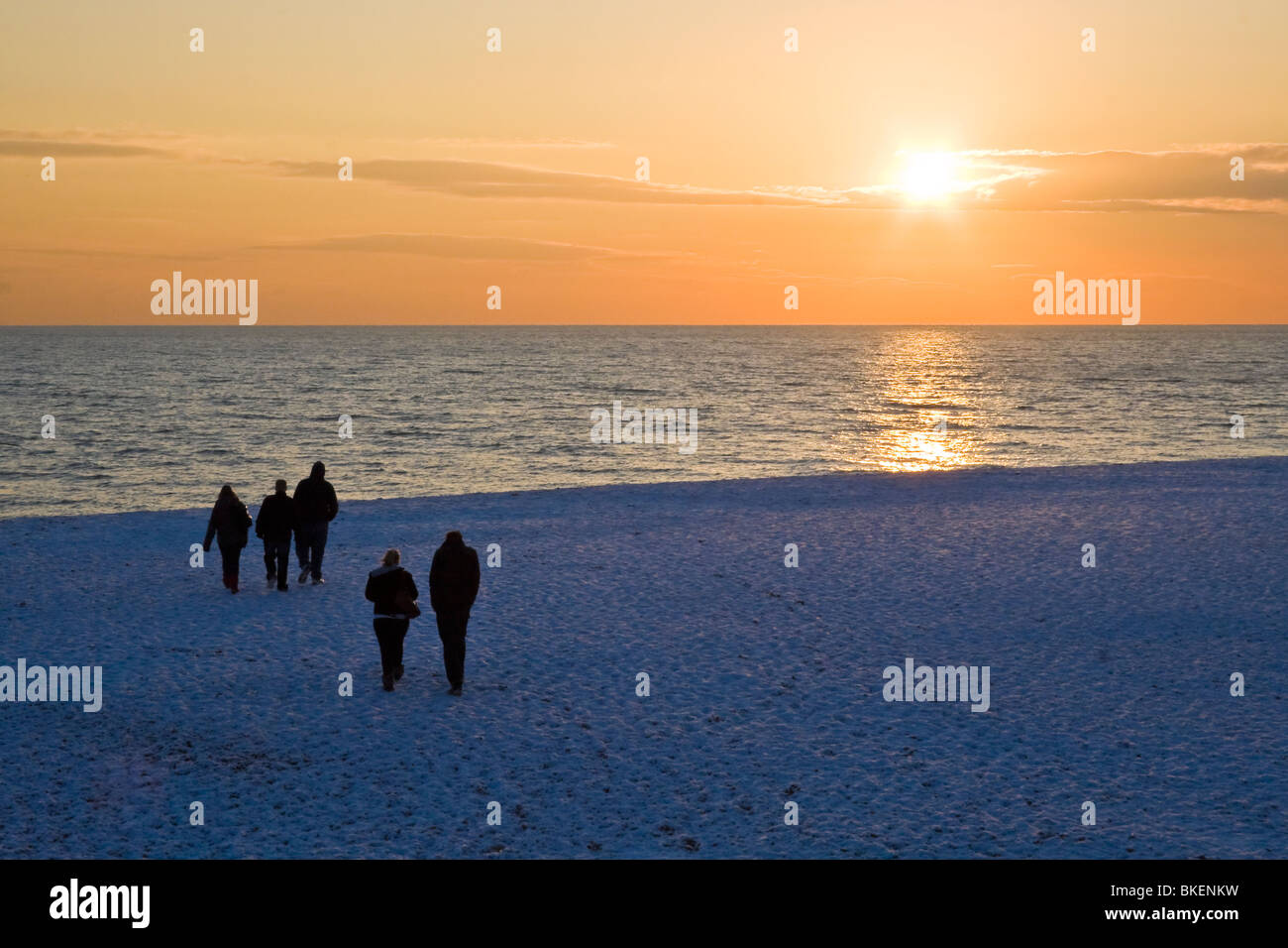 Silhouette de personnes sur la neige couverts plage au coucher du soleil. Brighton, UK JPH0266 Banque D'Images