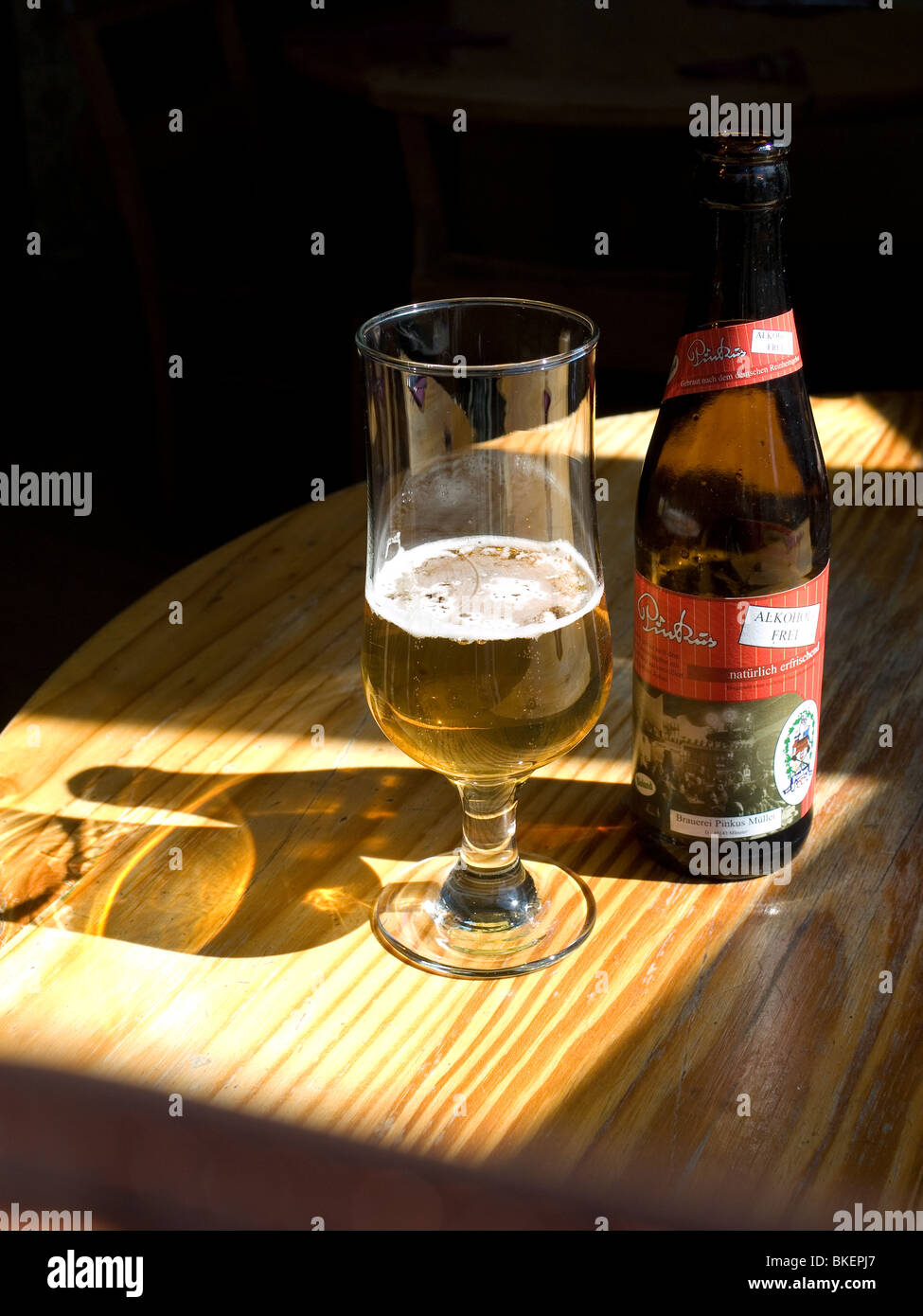 Soleil qui brille sur une partie et une bouteille de verre remplis d'alcool Lager allemande Pinkus Banque D'Images