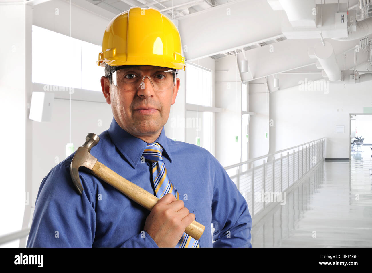 Hispanic construction manager holding hammer à l'intérieur du bâtiment Banque D'Images