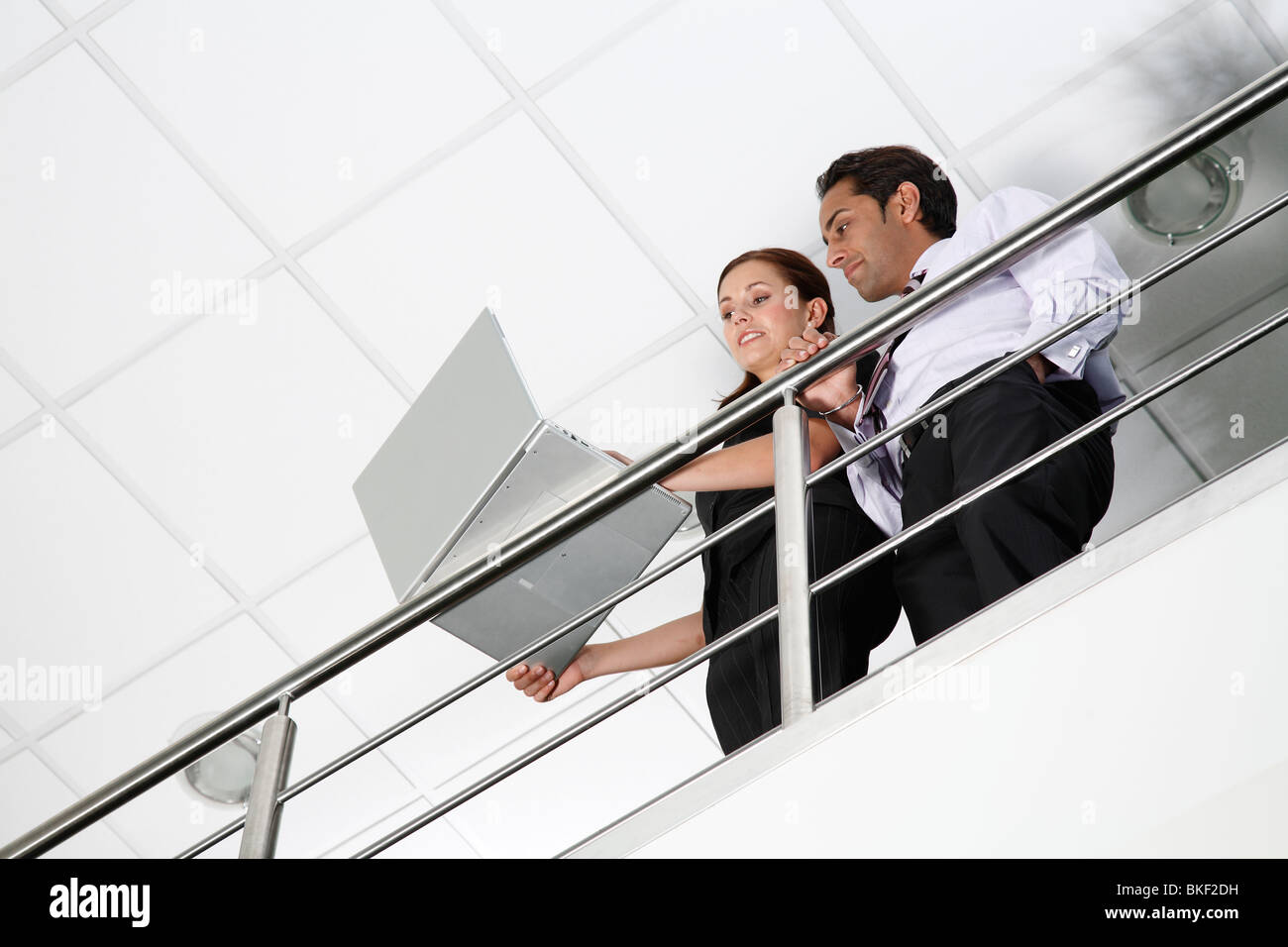 Asian male et femelle blanche des employés de bureau en bureau pour ordinateur portable à l'aide de l'environnement contemporain. Banque D'Images