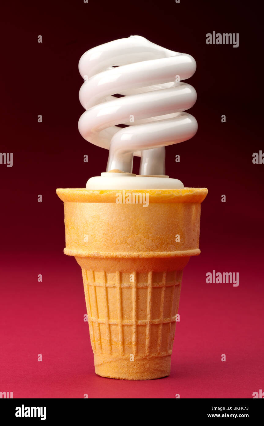 Une ampoule fluorescente compacte dans un cornet de crème glacée sur rouge Banque D'Images