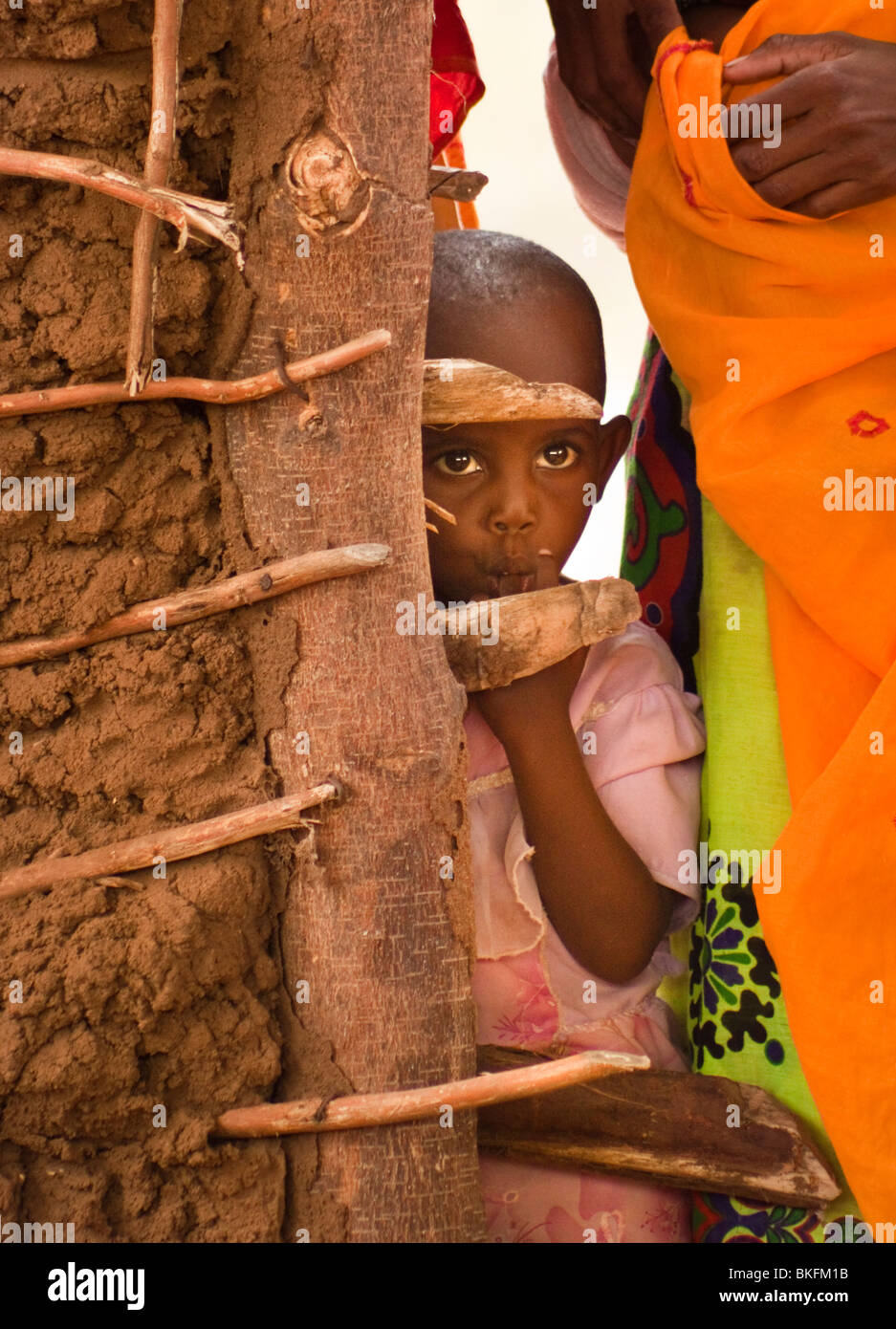 Jeune fille kenyane sur autour d'un mur de boue Banque D'Images