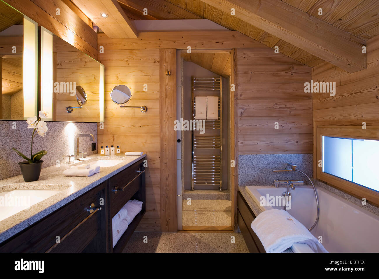 Des murs en bois et plafond en pente d'une salle de bains privative dans  chalet alpin moderne avec miroir au-dessus de l'éclairage Photo Stock -  Alamy