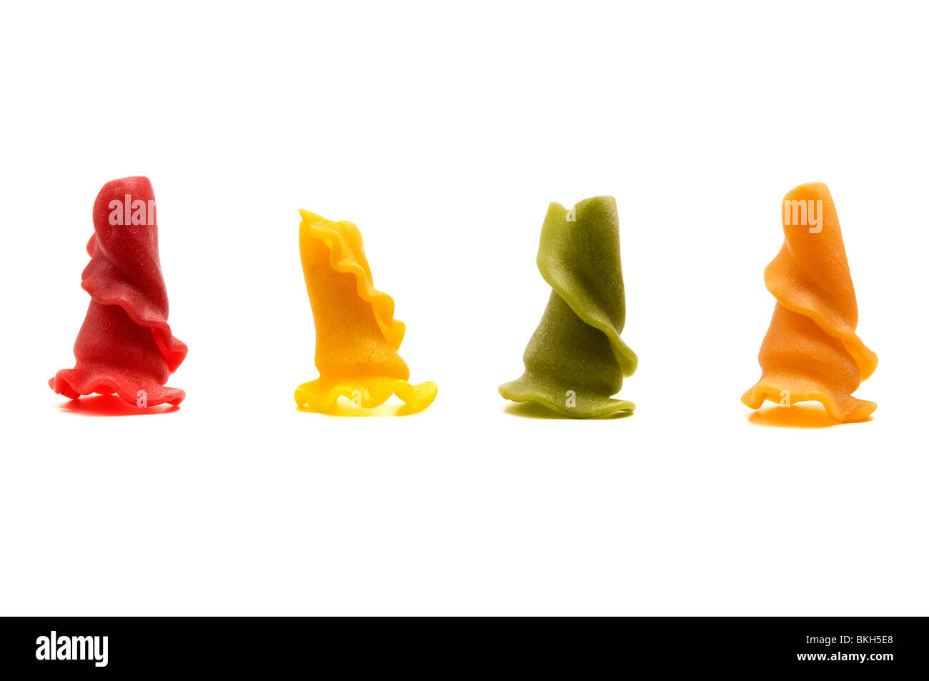 Pâtes en forme étrange mixte sur un fond blanc (Rouge  = Tomate, jaune  = blé dur, Vert  = les épinards, Orange  = Curcuma) Banque D'Images