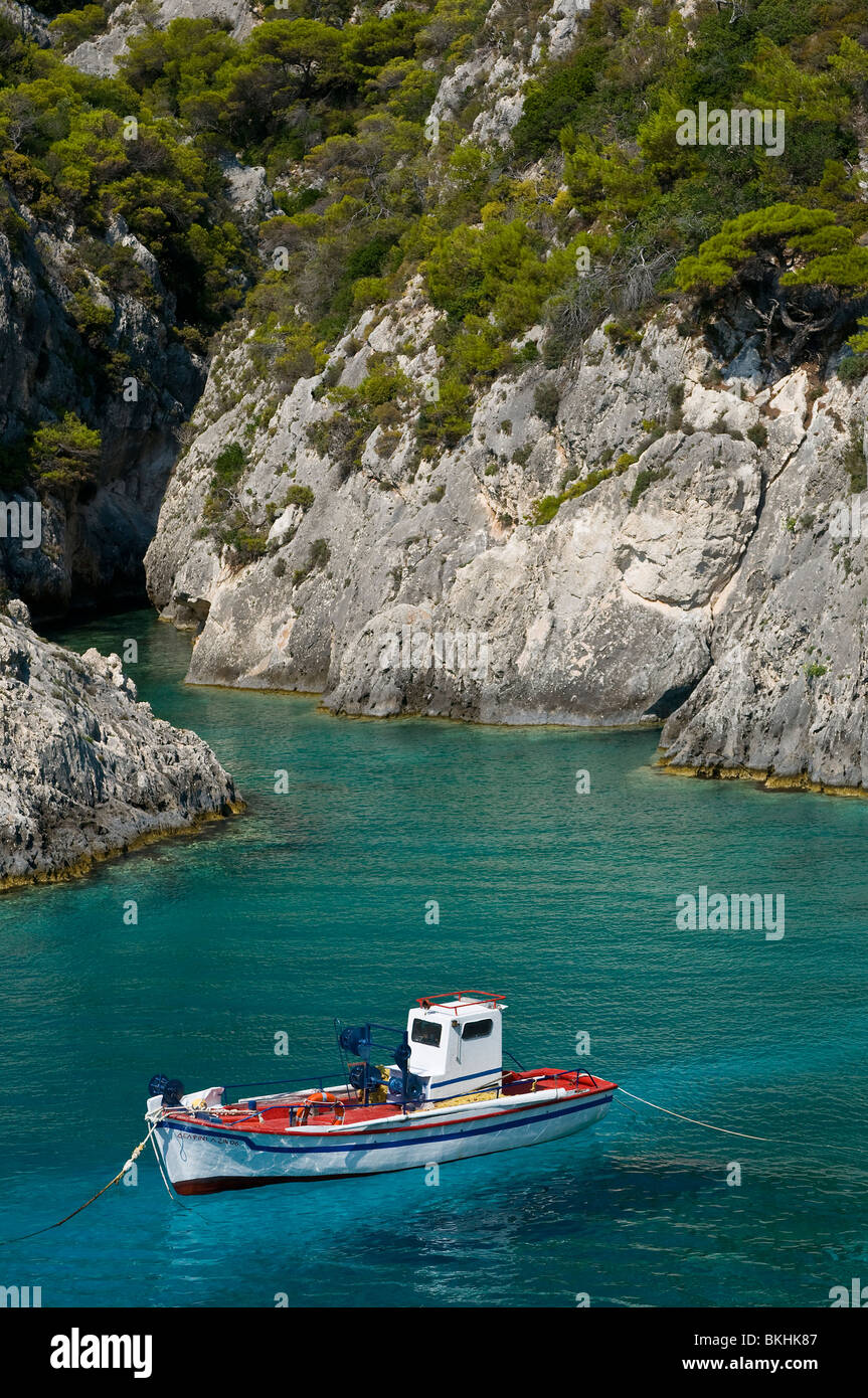 Petite baie rocheuse aux eaux cristallines et bateau touristique à Zakynthos, Grèce Banque D'Images