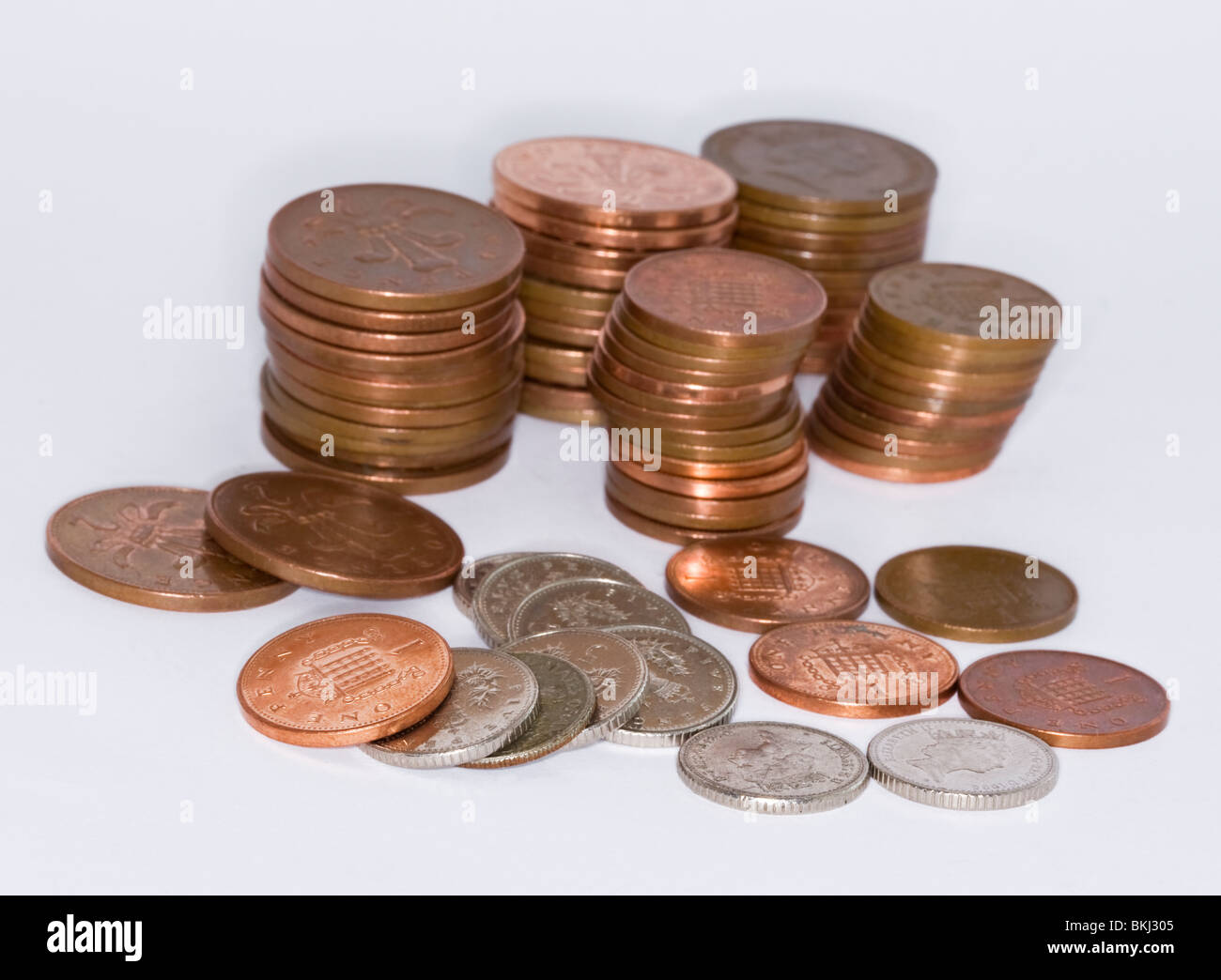 Des piles de pièces en anglais - deux pence et un Cinq pence pence morceaux sur un arrière-plan uni, blanc Banque D'Images