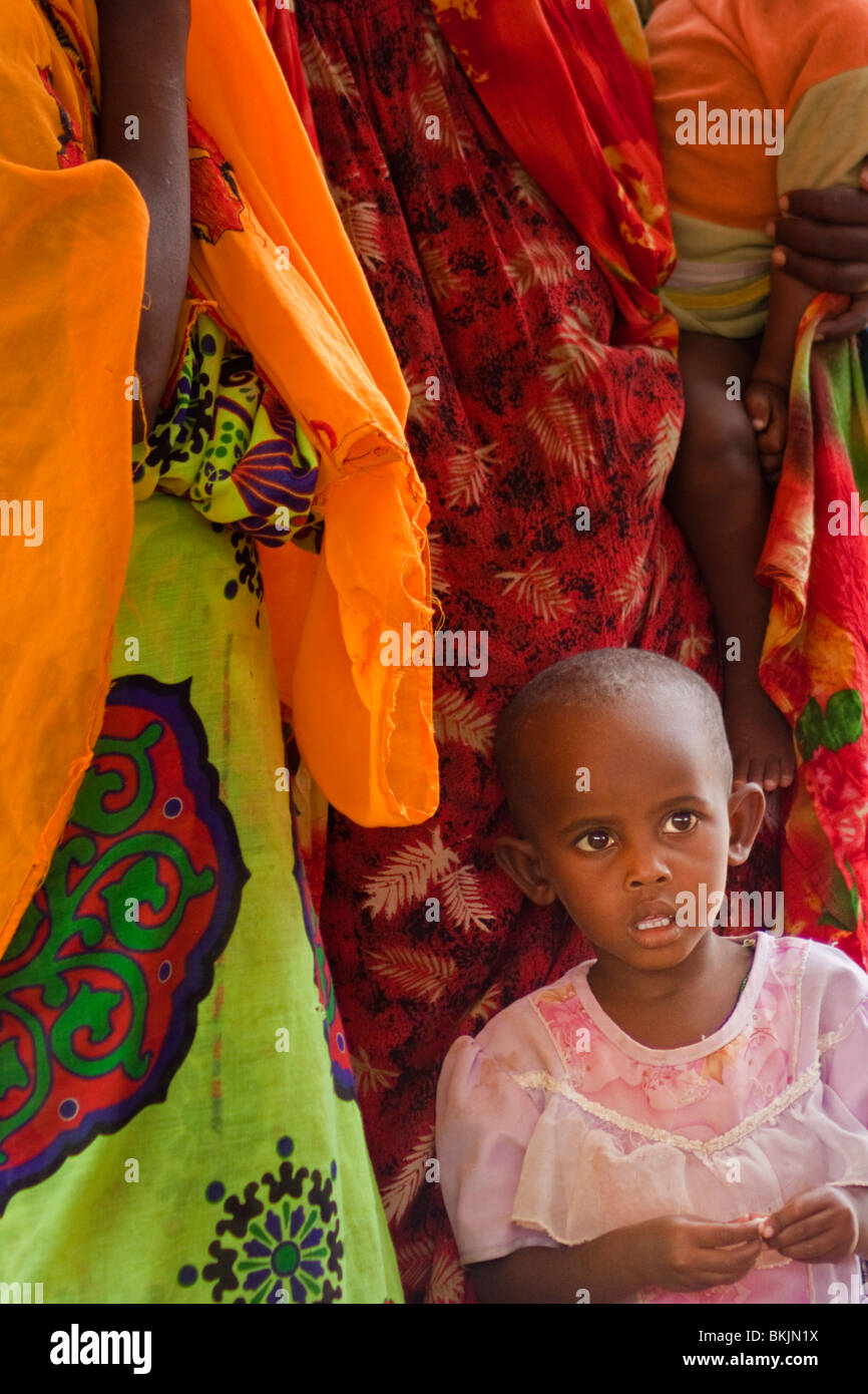 Jeune fille kenyane en rose en face de jupes de couleur Banque D'Images