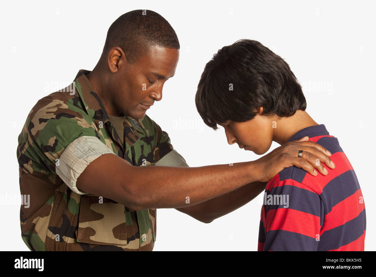 Un homme militaire priant pour un adolescent Banque D'Images