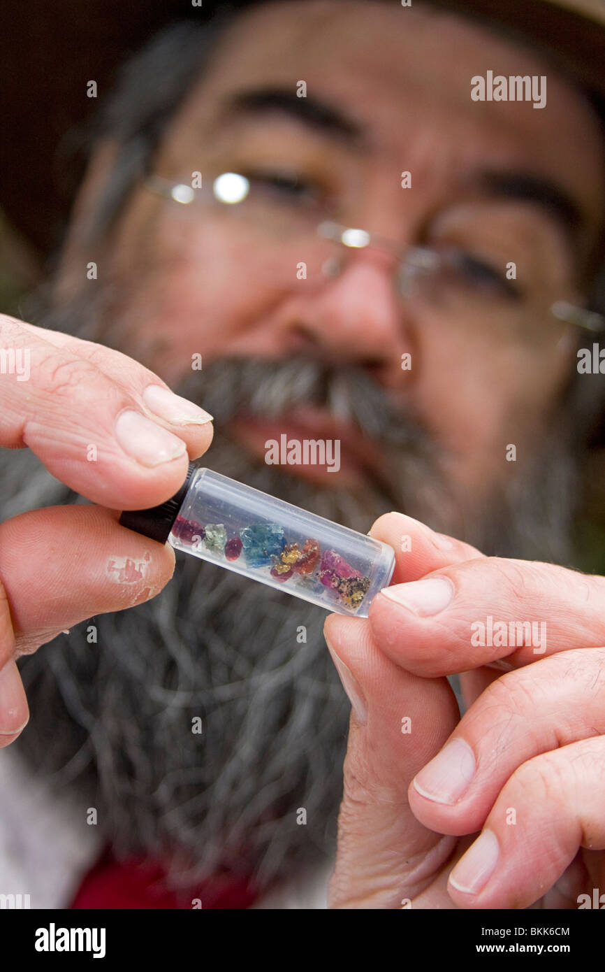 L'homme examine de près la fiole de verre gemmes de démonstration de techniques de l'orpaillage les années 1800 Banque D'Images