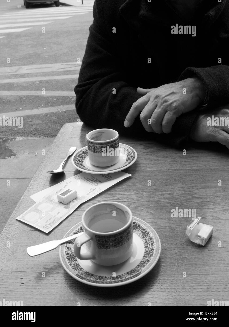 Homme mature assis devant un café à Paris Banque D'Images