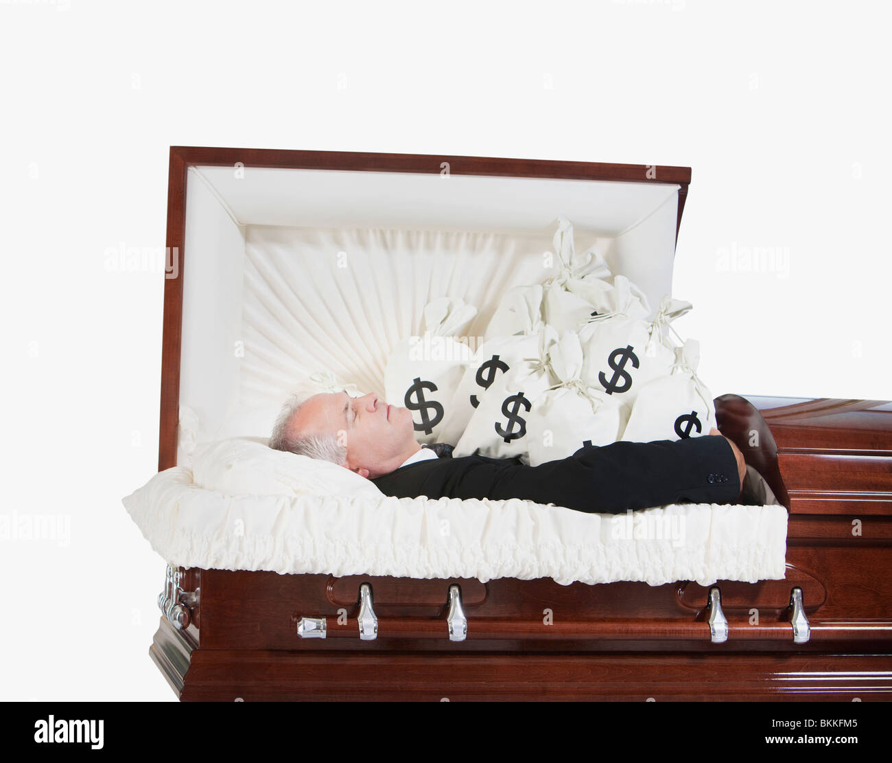 Un homme décédé dans un cercueil entouré de sacs d'argent Banque D'Images