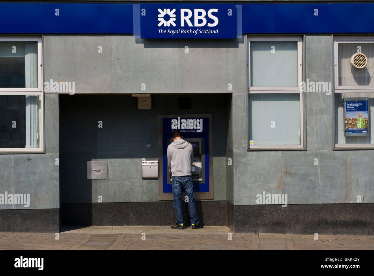 L'homme à l'aide d'une machine à sous à une succursale de la Royal Bank Of Scotland Banque D'Images