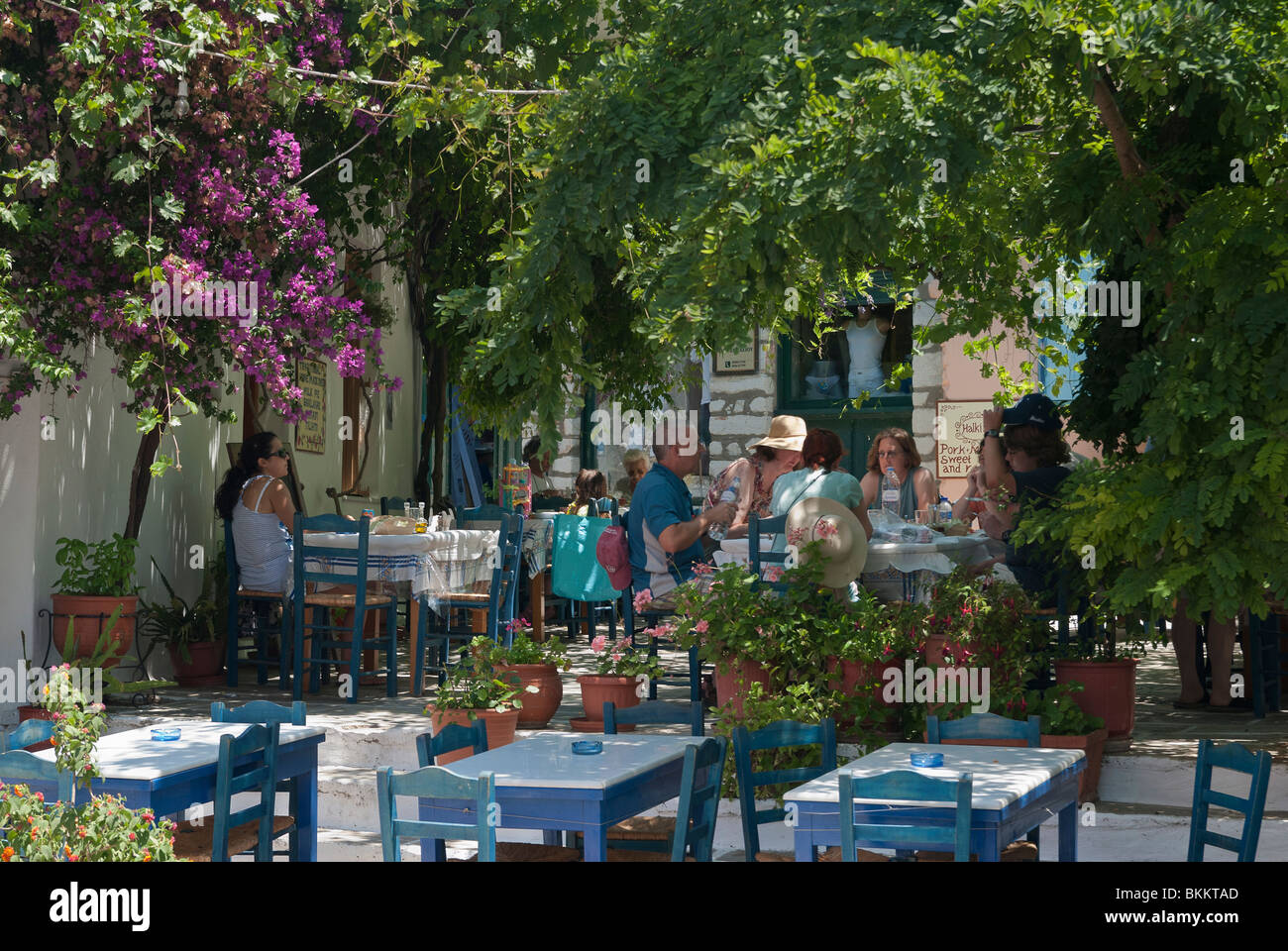 Les touristes appréciant le déjeuner dans une place ombragée d'arbres dans l'île de Chalki, Naxos, Grèce Banque D'Images