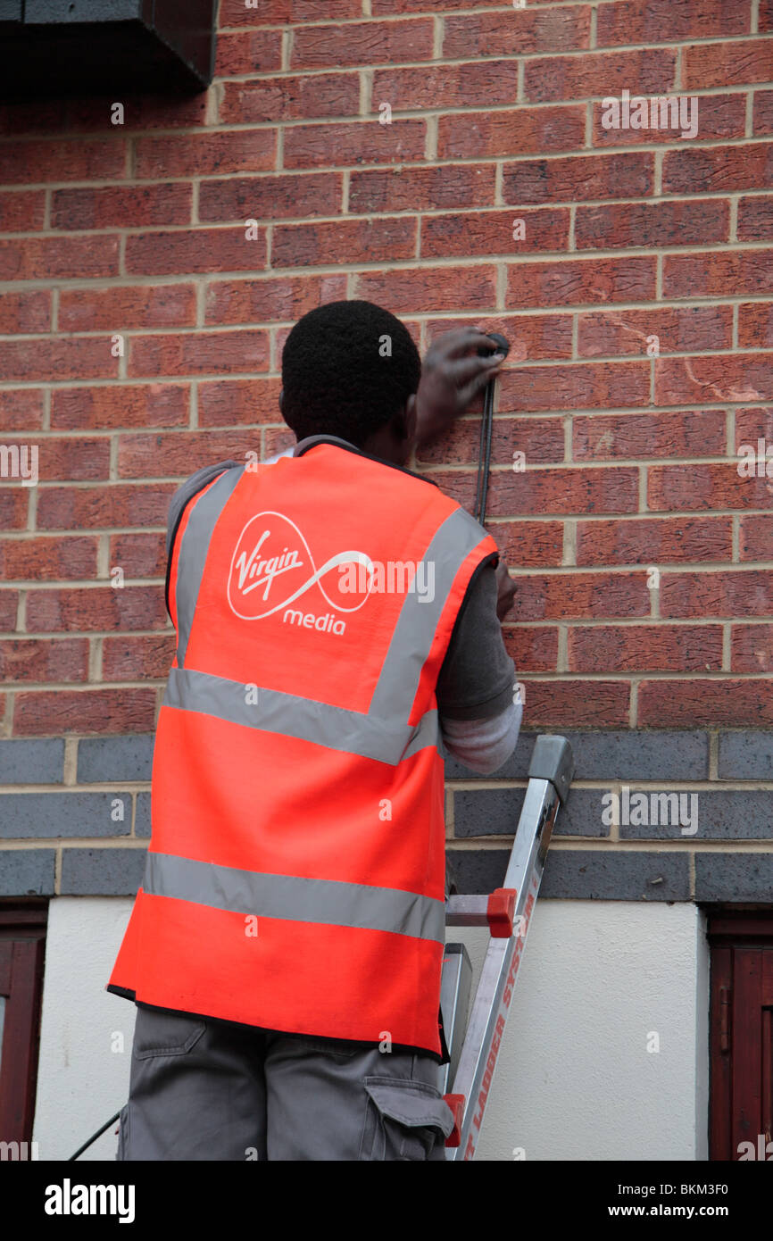 Un ingénieur de support vierge de l'installation d'un nouveau service de télévision par câble/large bande à un premier étage télévision à Hounslow, Royaume-Uni. Banque D'Images