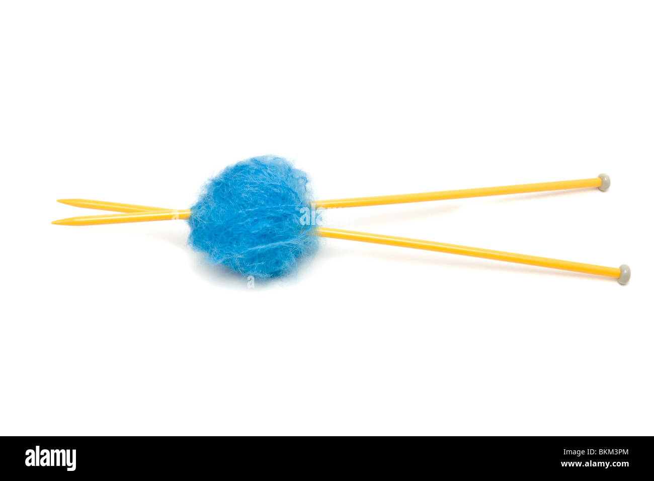 Une petite balle de laine mohair bleu percé avec de grandes aiguilles à tricoter jaune contre blanc. Banque D'Images
