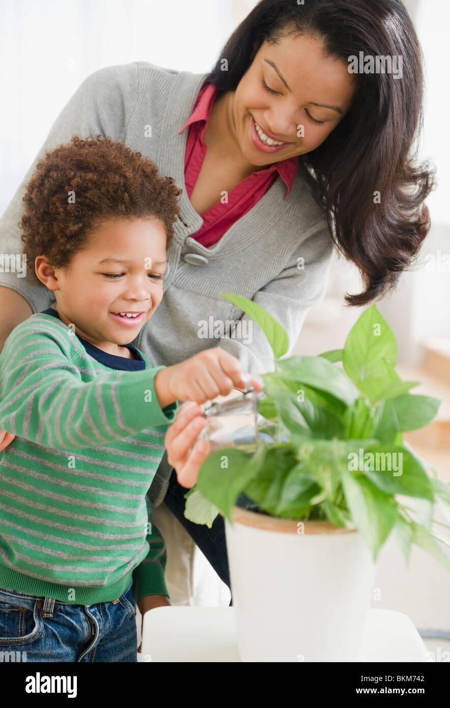 Mixed Race mother helping son plantes de l'eau Banque D'Images