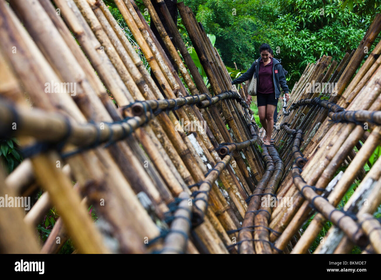 Une femme traverse un pont de bambou Bidayuh le Village Culturel de Sarawak, le Damai Beach. Kuching, Sarawak, Bornéo, Malaisie. Banque D'Images