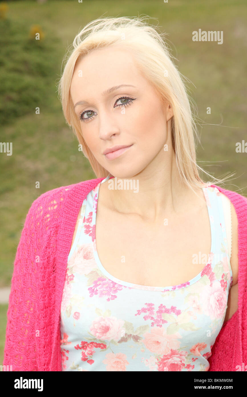 Portrait d'une jolie fille blonde portant un cardigan rose à la recherche à l'appareil photo Banque D'Images