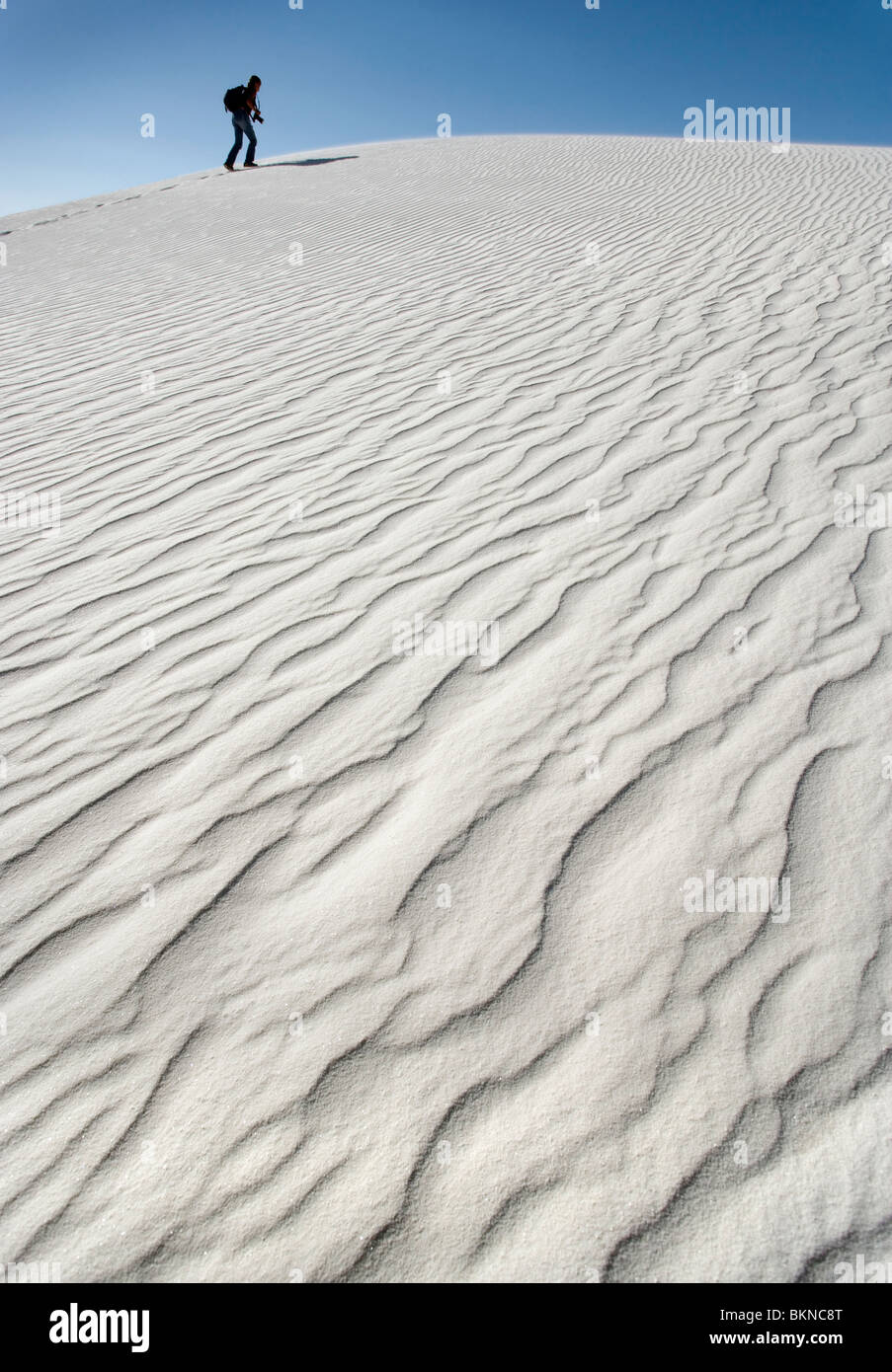 Une personne qui marche d'une grande dune de sable blanc au White Sands National Monument, Nouveau-Mexique. Banque D'Images