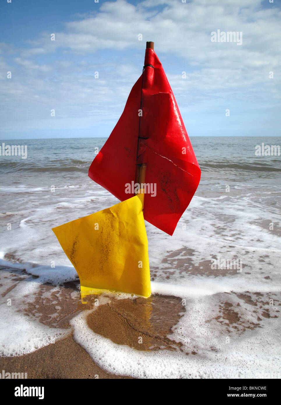 Lavé en rouge et jaune / pêche le homard drapeaux marqueurs positionnés sur la plage à marée montante. Banque D'Images