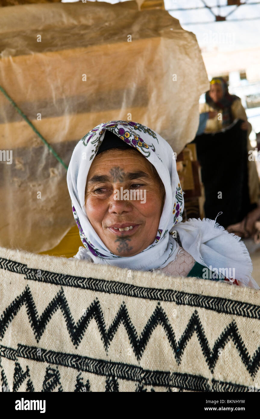 Une femme berbère tapis traditionnels de vente dans un marché dans la région du Moyen Atlas du Maroc. Banque D'Images