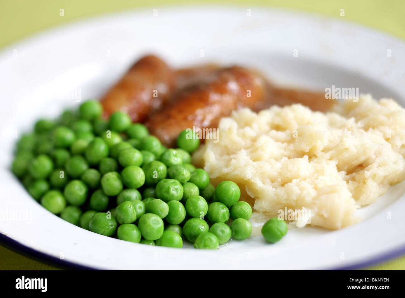 Réchauffement britannique traditionnel confort alimentaire de saucisses de porc avec de la purée de pommes de terre, petits pois et sauce servi sur une plaque avec aucun peuple Banque D'Images