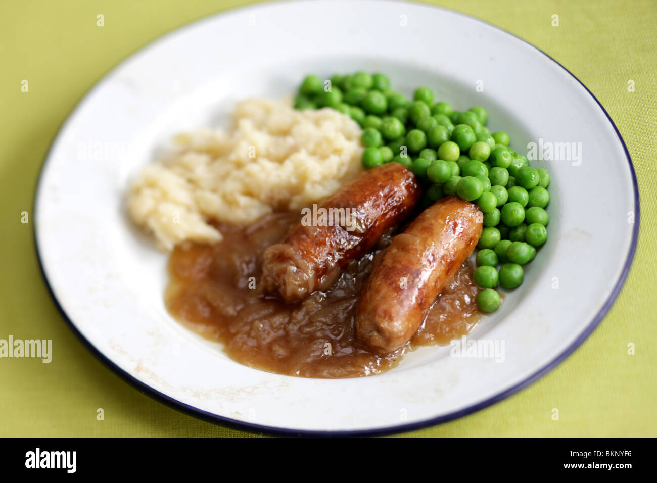 Réchauffement britannique traditionnel confort alimentaire de saucisses de porc avec de la purée de pommes de terre, petits pois et sauce servi sur une plaque avec aucun peuple Banque D'Images