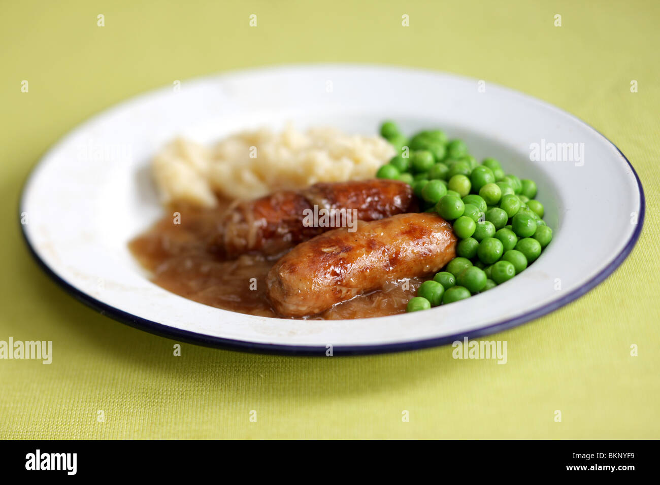 Réchauffement britannique traditionnel confort alimentaire de saucisses de porc avec de la purée de pommes de terre, petits pois et sauce servi sur une plaque avec aucun peuple Banque D'Images