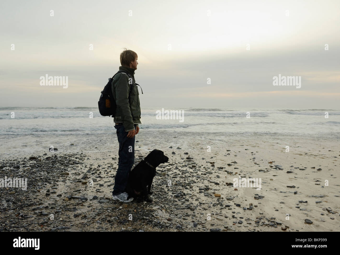 Cadix, Andalousie, Espagne ; un homme sur Arte y Vida Beach avec son chien labrador noir à Tarifa, Costa De La Luz Banque D'Images