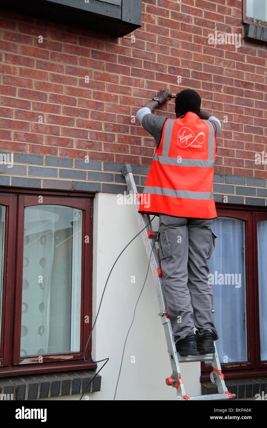 Un ingénieur de support vierge de l'installation d'un nouveau service de télévision par câble/large bande à un premier étage télévision à Hounslow, Royaume-Uni. Banque D'Images