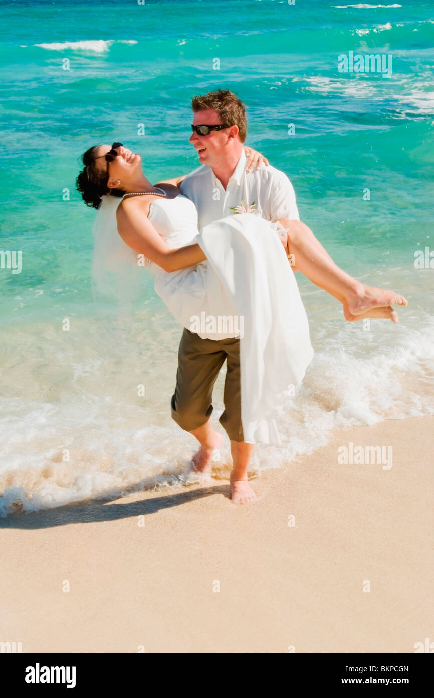 Akumal, Riviera Maya, Mexique ; un groom transportant la mariée sur la plage de Gran Bahia Principe Tulum All-Inclusive Resort Banque D'Images
