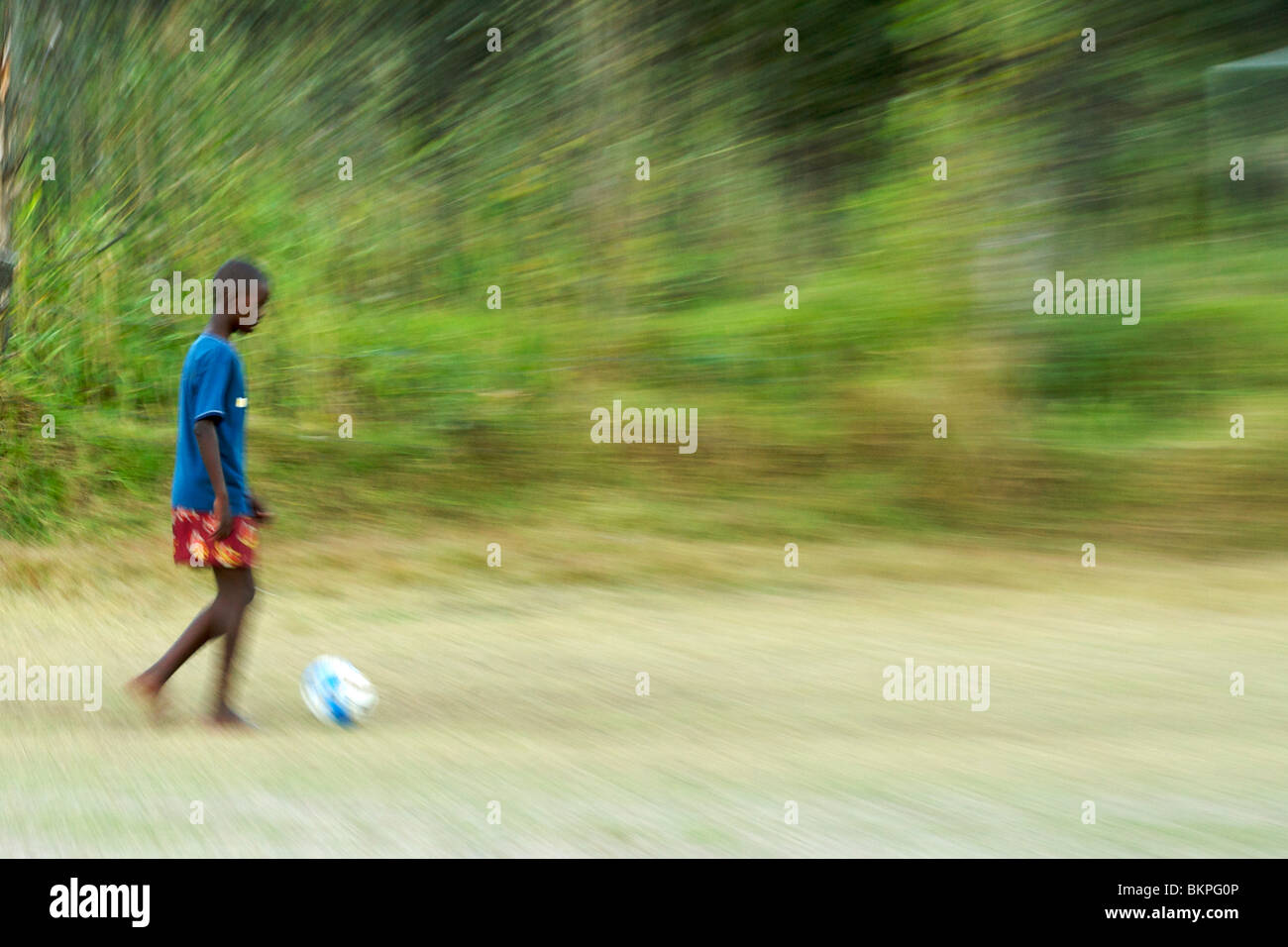 En Afrique, un enfant jouant au football pieds nus dans un champ à Hout Bay, à Cape Town, Afrique du Sud. Banque D'Images