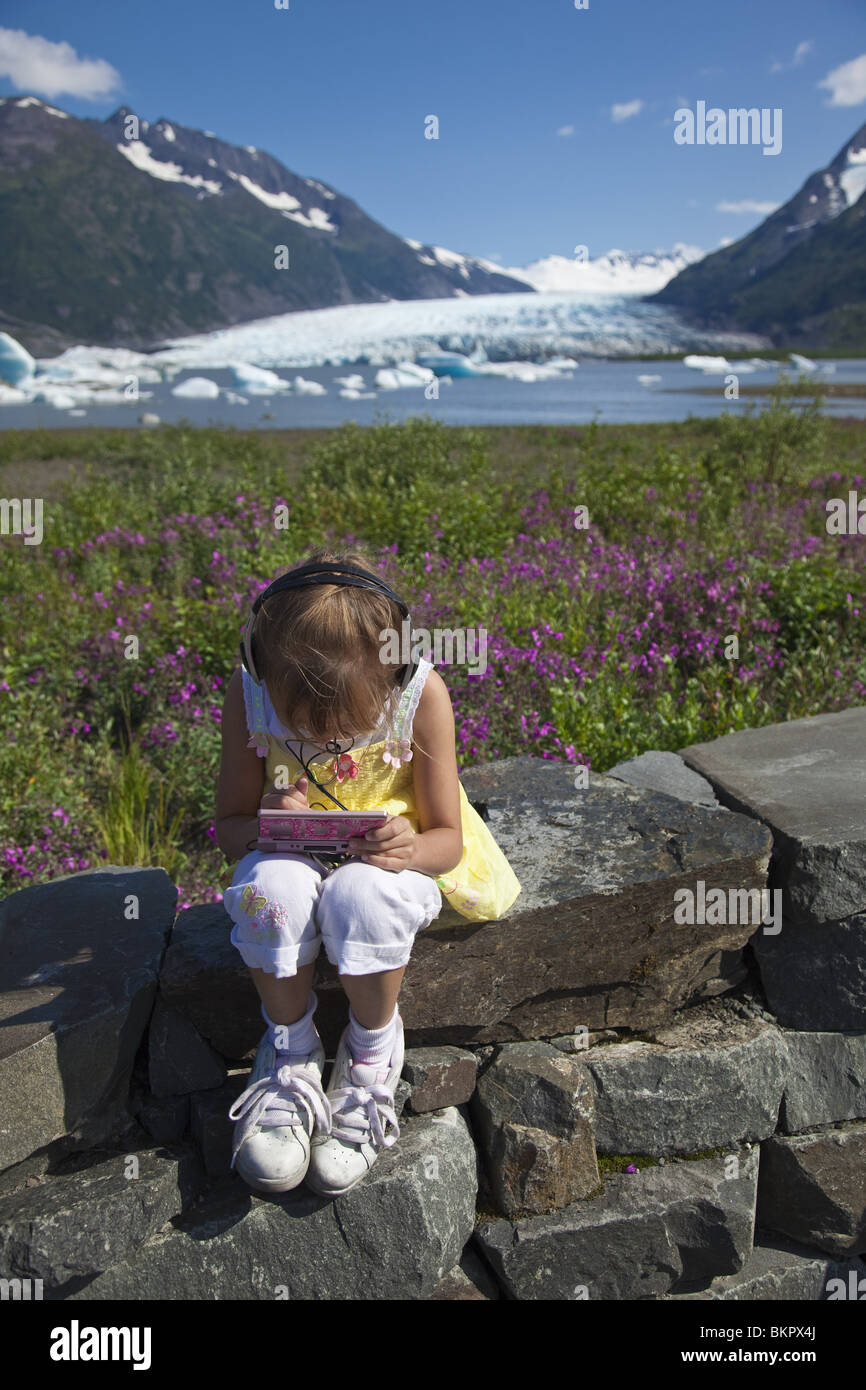 Jeune fille joue un jeu électronique à la plate-forme d'observation du Service des forêts pour Spencer Glacier in Southcentral Alaska Banque D'Images