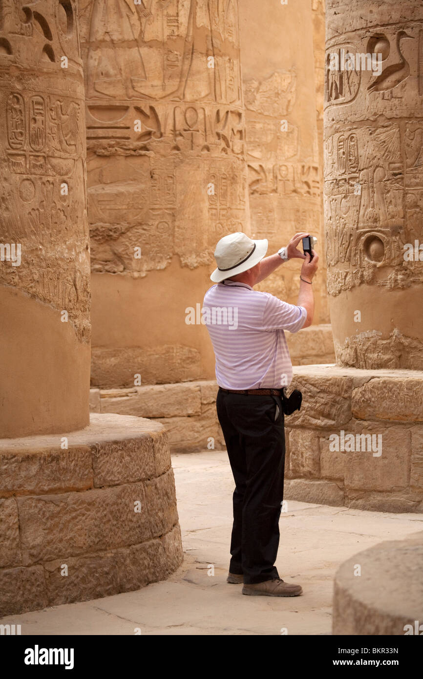 Egypte, Karnak. Un touriste photographie les colonnes en pierre massive dans la salle hypostyle. Banque D'Images