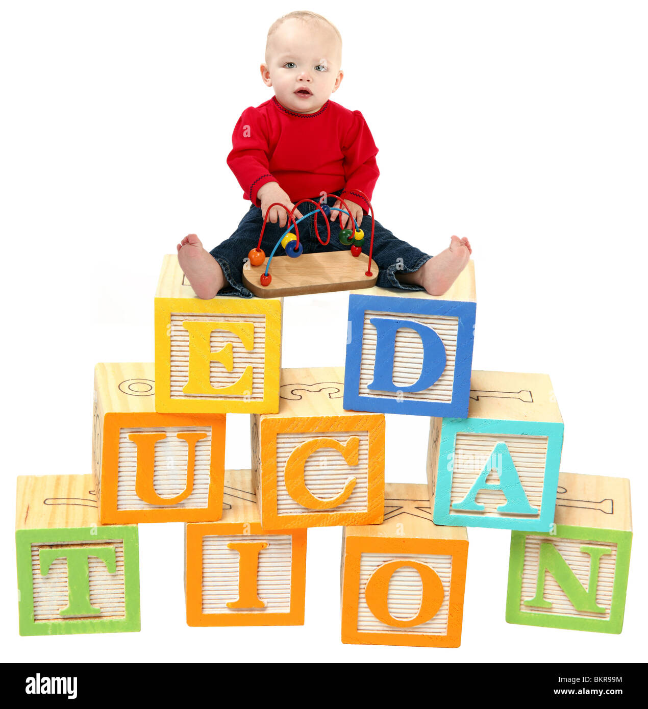 14 mois baby girl sitting on colorful toy blocks que lire l'éducation. Banque D'Images