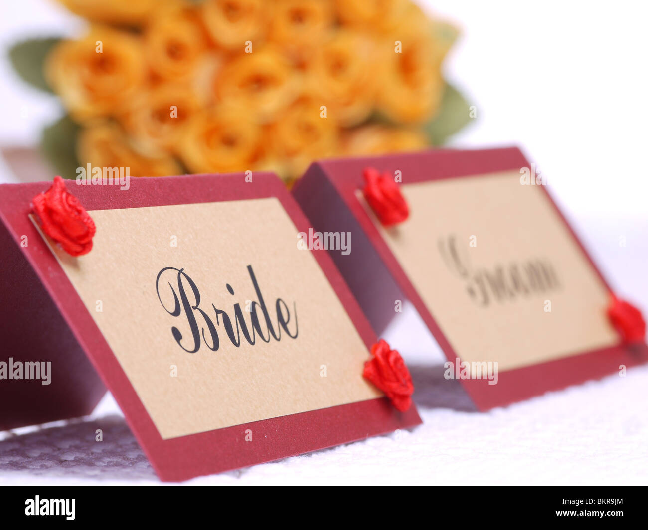 Mariée et le marié nom cartes sur une table de mariage avec bride's bouquet de roses jaunes à l'arrière-plan Banque D'Images