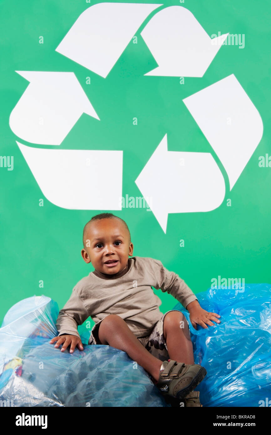Un jeune garçon avec des sacs de recycler les Recycle Sign Banque D'Images