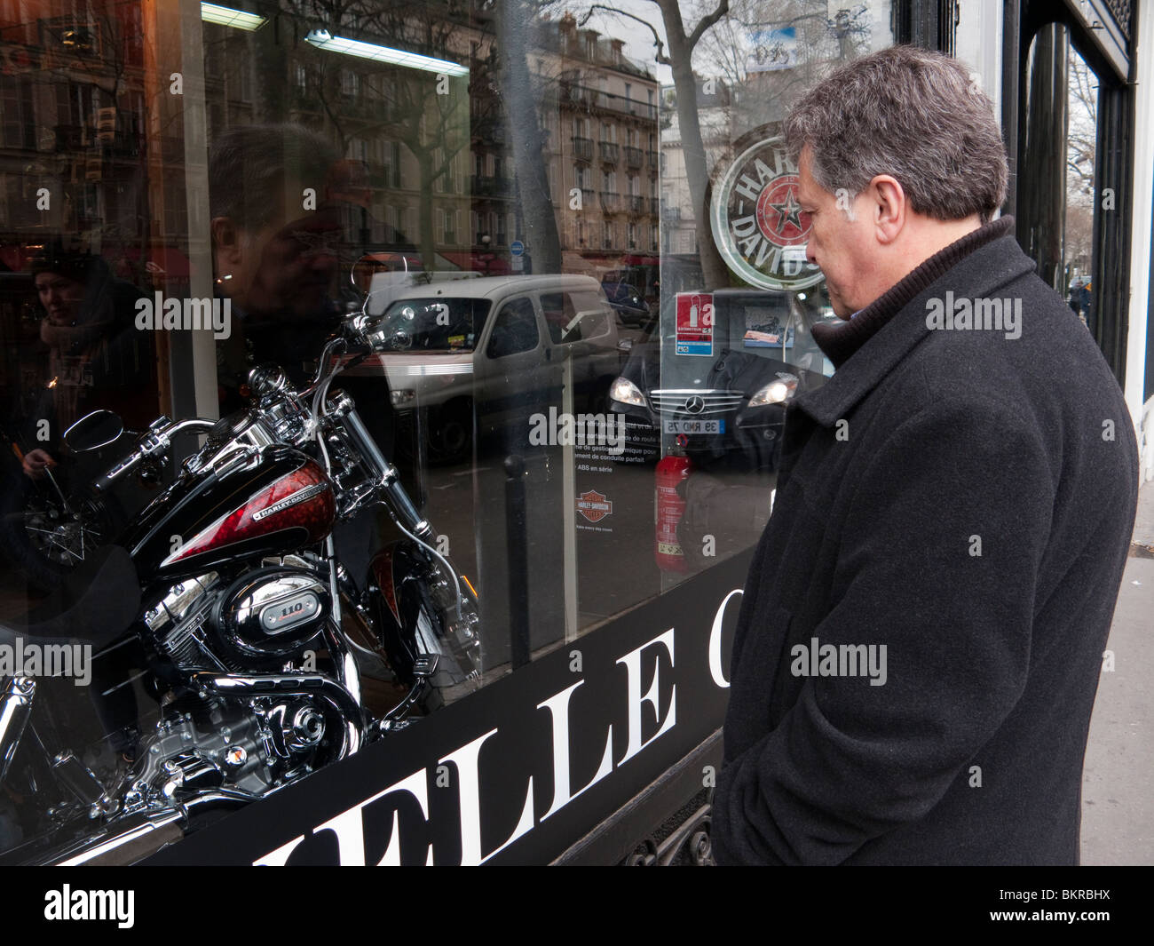 Homme mature à la recherche à une Harley Davidson moto dans une vitrine Banque D'Images